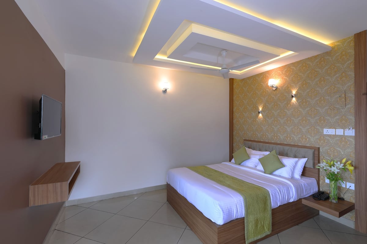A modern bedroom with a bed, bedside table, wall-mounted TV, and decorative wall lights.