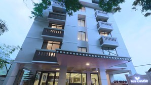 A multi-story hotel with a modern design, featuring balconies, large windows, and a reception area. - Tea Castle Munnar (Devikolam)
