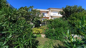 A multi-story residential building with balconies, surrounded by lush greenery and a clear blue sky. - Apartment Marija (Novi Vinodolski)