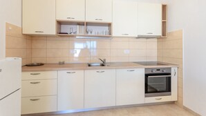 A modern kitchen with white cabinets, a built-in oven, and a stainless steel sink. - Apartment Marija (Novi Vinodolski)