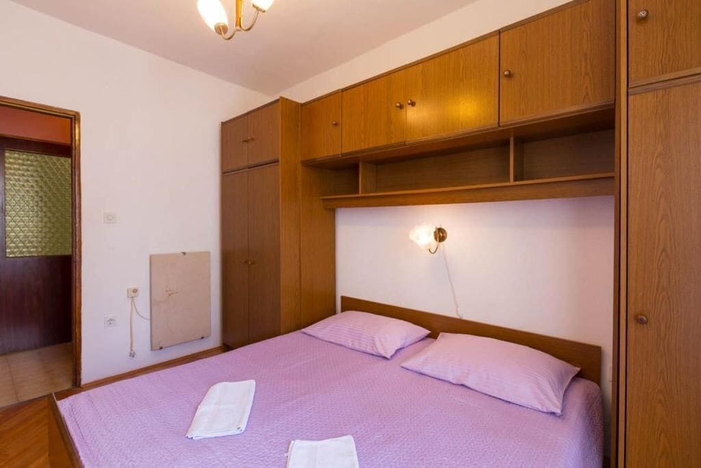 Ein Schlafzimmer mit einem Bett, Holzschränken und einer Wandleuchte.