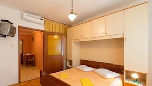 A bedroom with a wooden bed, a nightstand with a lamp, and a wardrobe. - Apartments Vodaric (Mali Losinj)