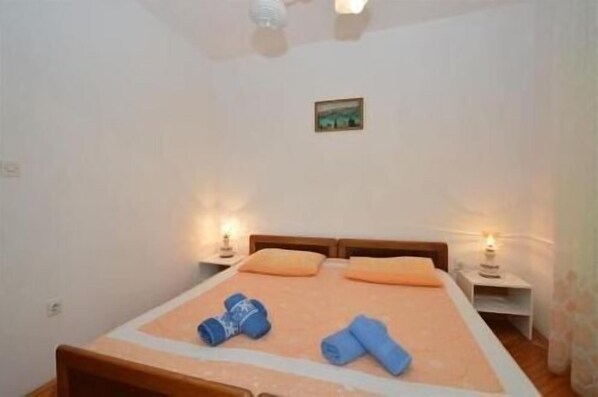 A bedroom with a bed, two bedside tables, and a small picture on the wall. - Apartments Vodaric (Mali Losinj)
