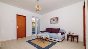 Un salon avec un canapé, une table basse, un tapis, une porte et un tableau au mur.