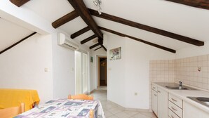 A room with a dining table, a kitchen with a sink, and a hallway leading to another room. - Apartment Mauro (Punat)
