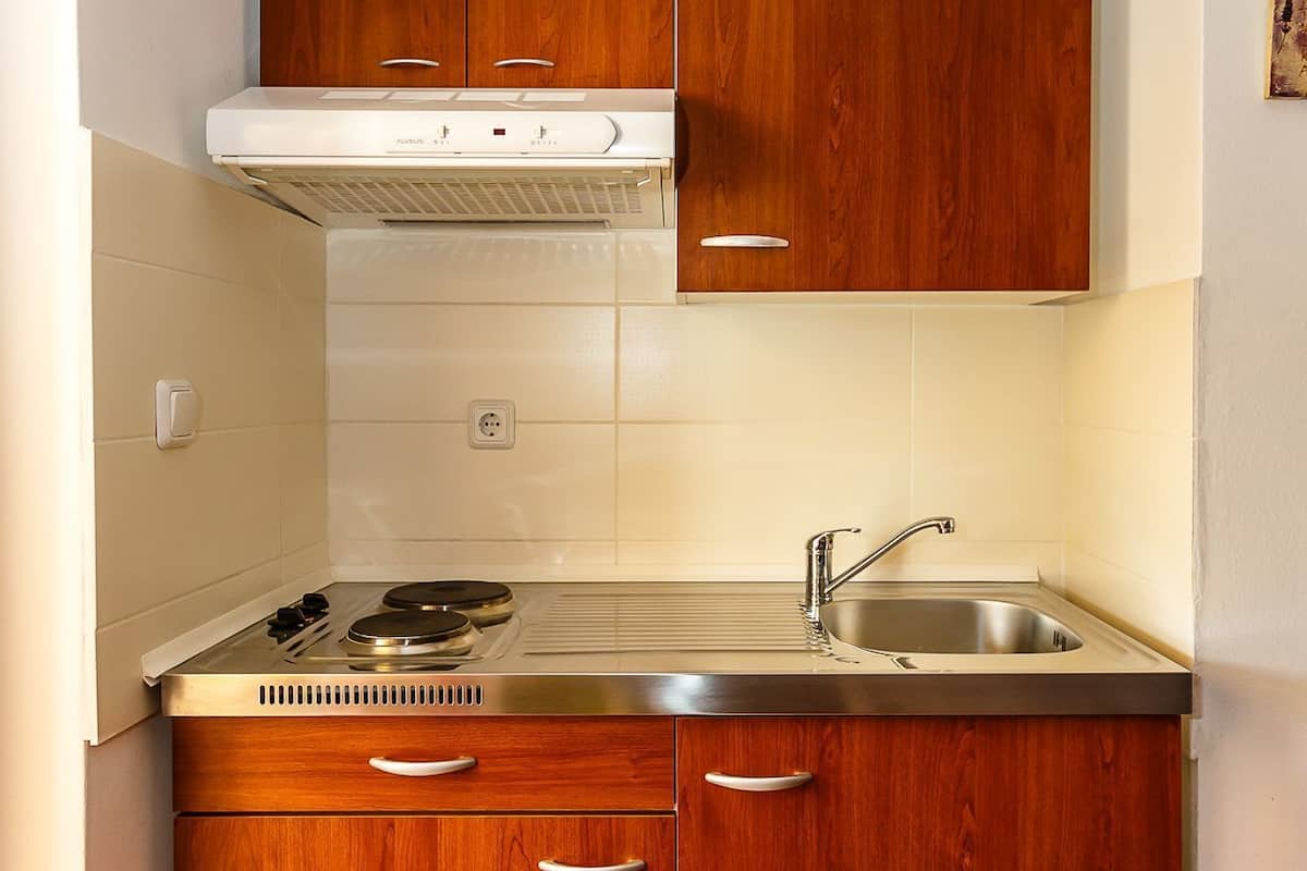A compact kitchen with wooden cabinets, a stainless steel sink, and a built-in stove.