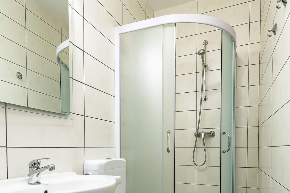 A modern bathroom with a white sink, toilet, and glass-enclosed shower.