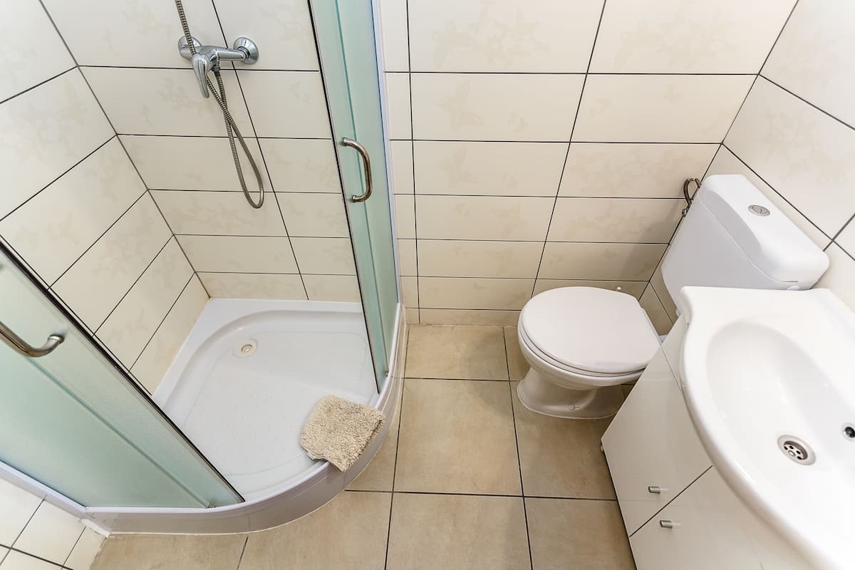 A bathroom with a glass-enclosed shower, a toilet, and a sink.
