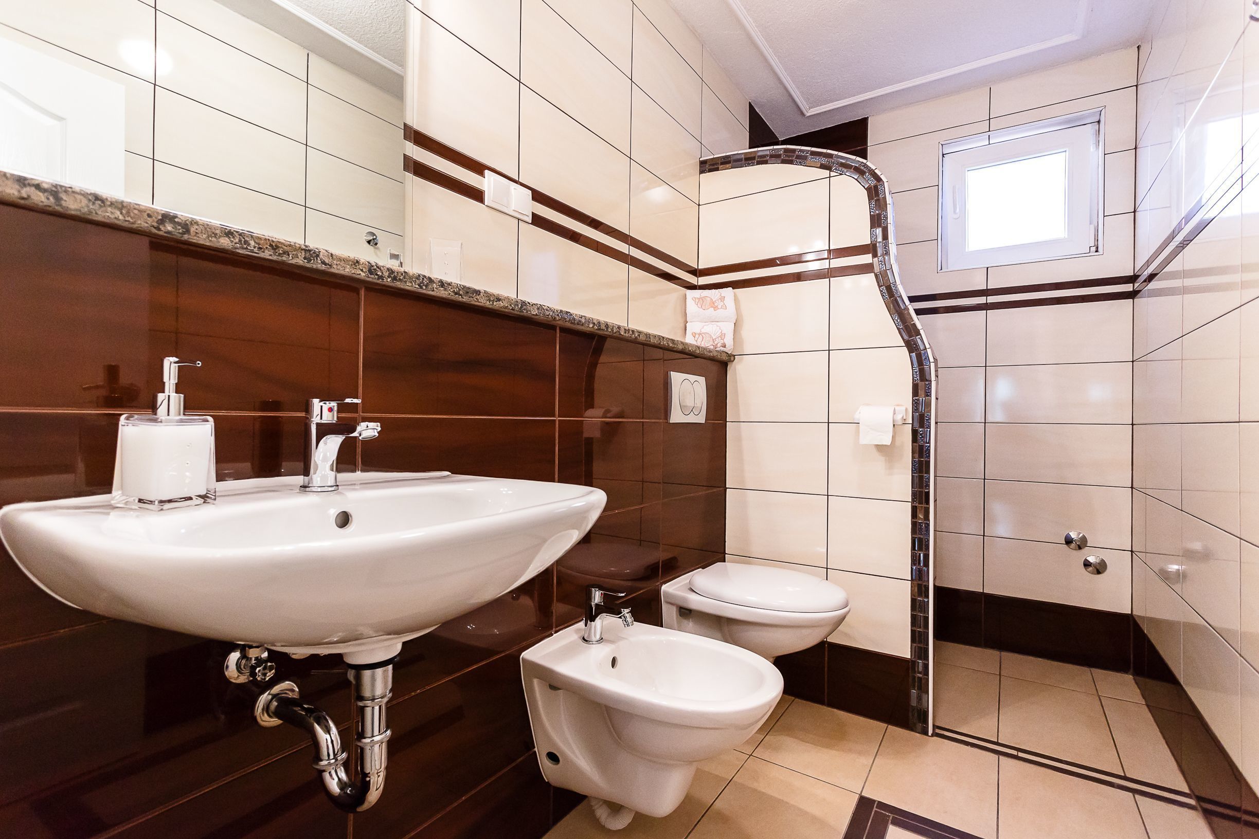 Een badkamer met een grote wastafel, toilet, douche en een bidet.