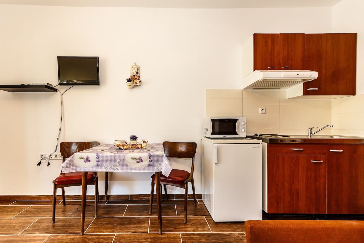 A compact kitchen with a dining table, chairs, a microwave, and wooden cabinets.