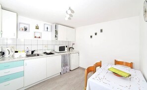 A modern kitchen with white cabinets, a microwave, and a dining table with chairs.