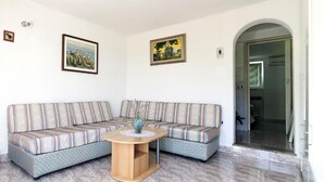 A living room with a corner sofa, a round wooden coffee table, and two framed pictures on the walls. - Apartment Sanja (Brsec)