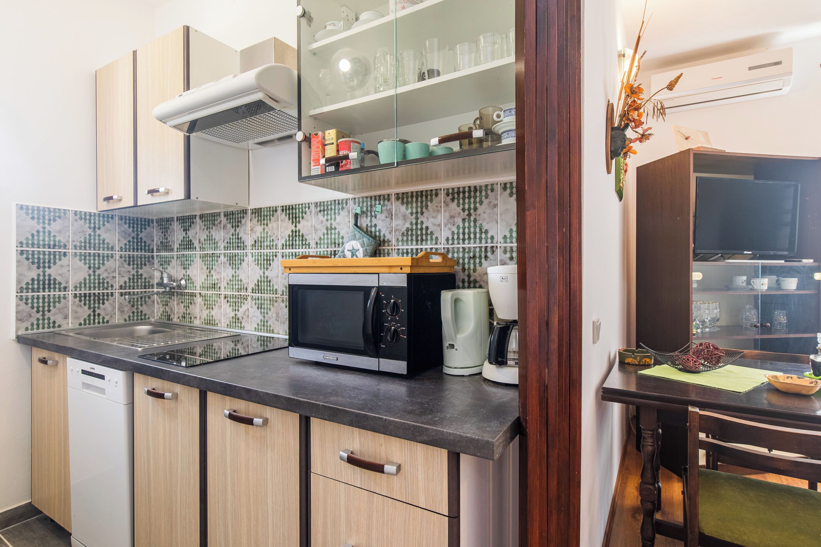Una cucina con forno a microonde, macchina del caffè e zona pranzo con tavolo e sedie.