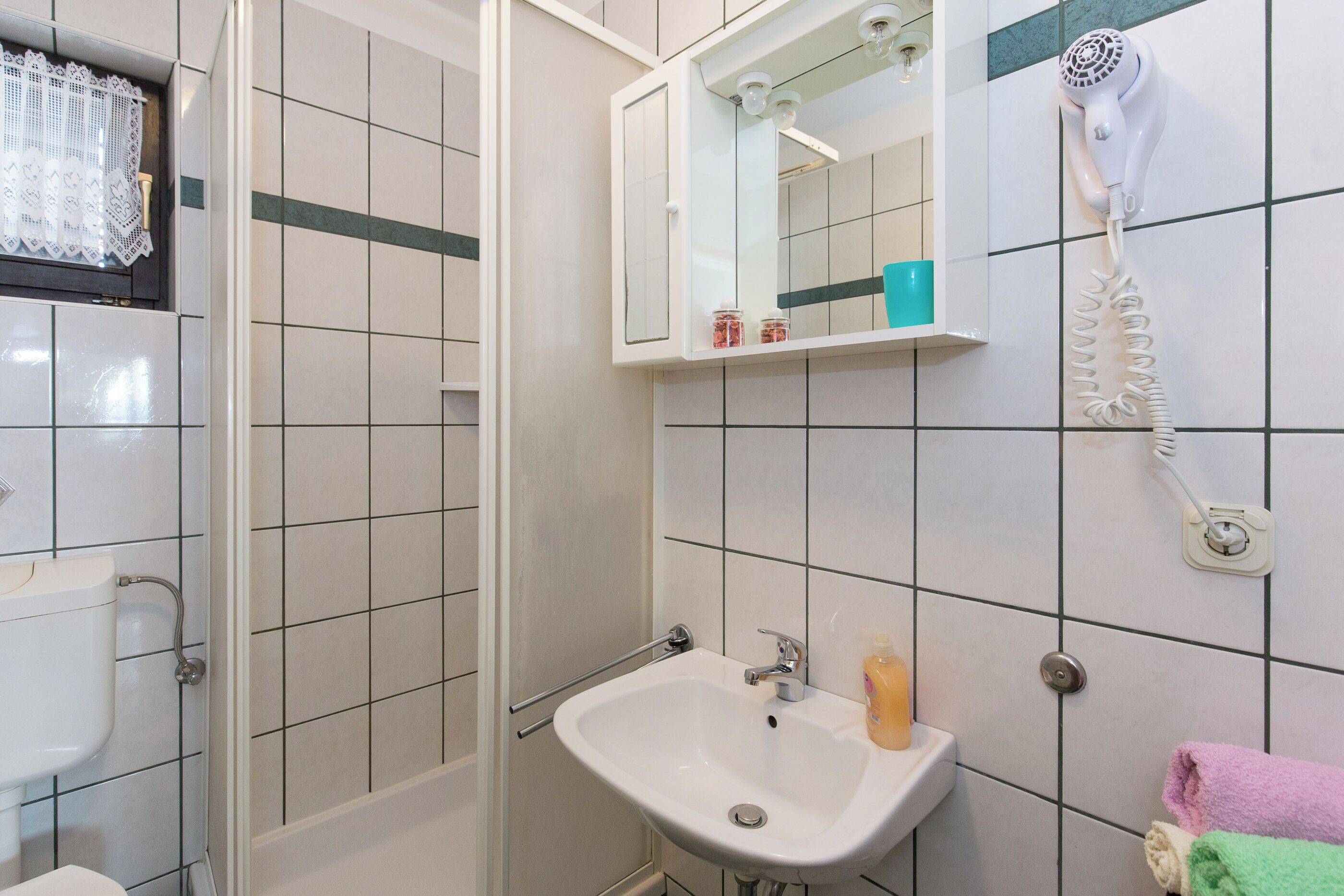 Une salle de bain équipée d’un lavabo, d’un miroir, d’un sèche-cheveux et d’un porte-serviettes.