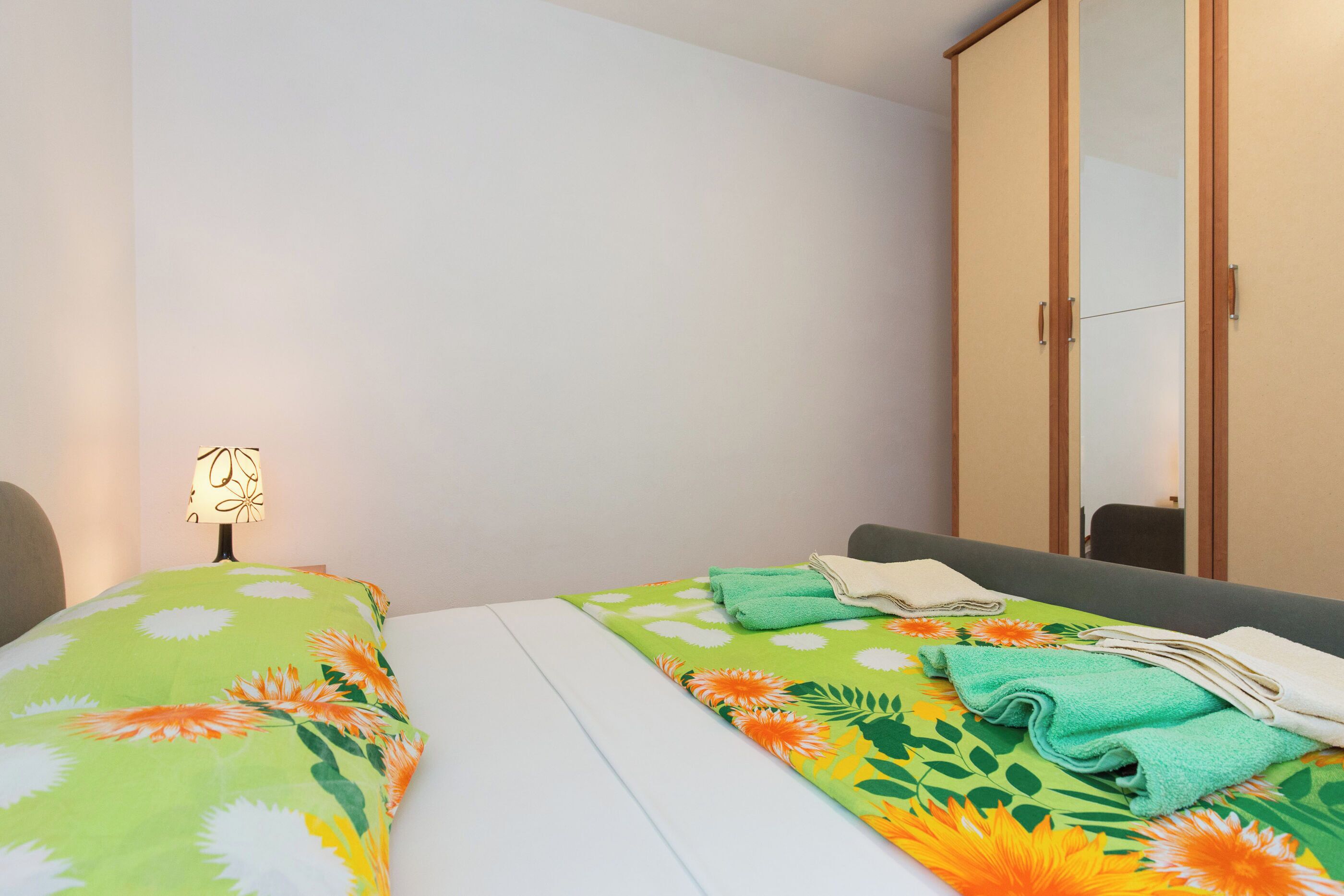 A hotel room with a bed, a nightstand, a lamp, and a wardrobe.