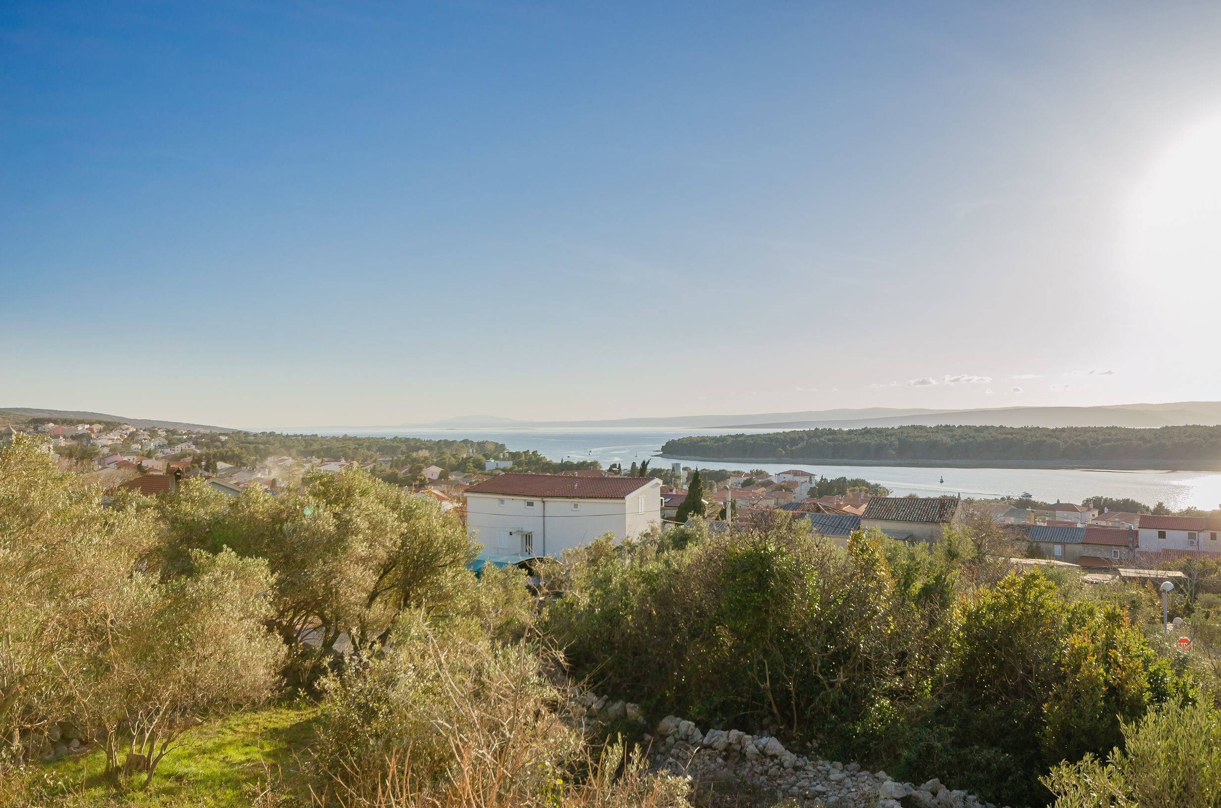 A coastal town with a view of the sea and a large white building in the foreground.