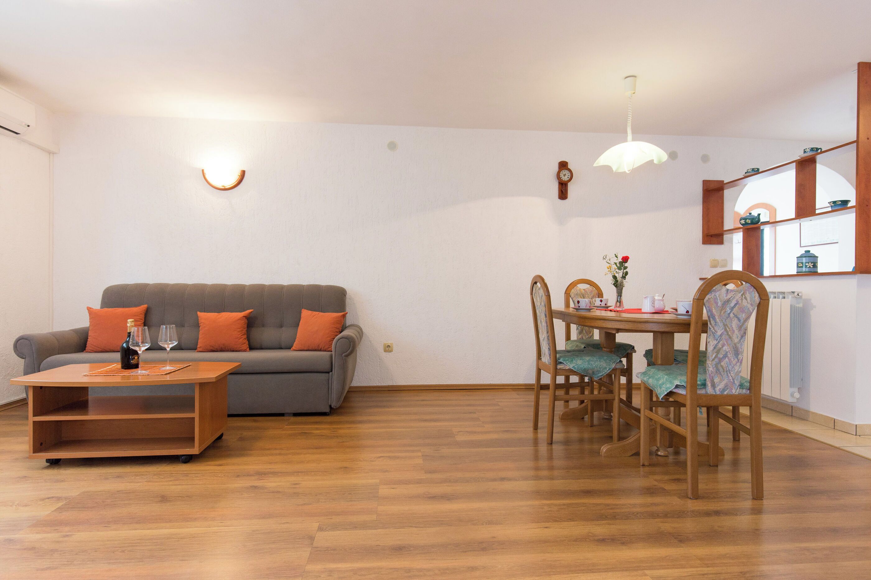A living room with a sofa, coffee table, dining table, chairs, and a pendant light.