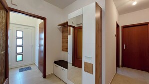 A hallway with a wardrobe, a door with a mirror, and a wooden door. - Apartment Neda (Punat)