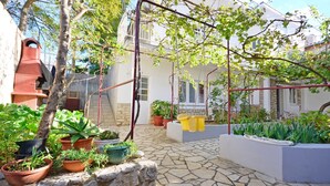 A courtyard with potted plants, a stone floor, and a building with balconies. - Apartments Jasminka (Selce)