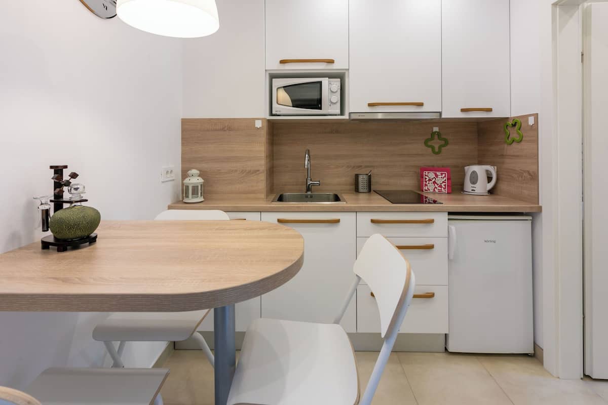 Een kleine keuken met een magnetron, spoelbak en een koelkast.