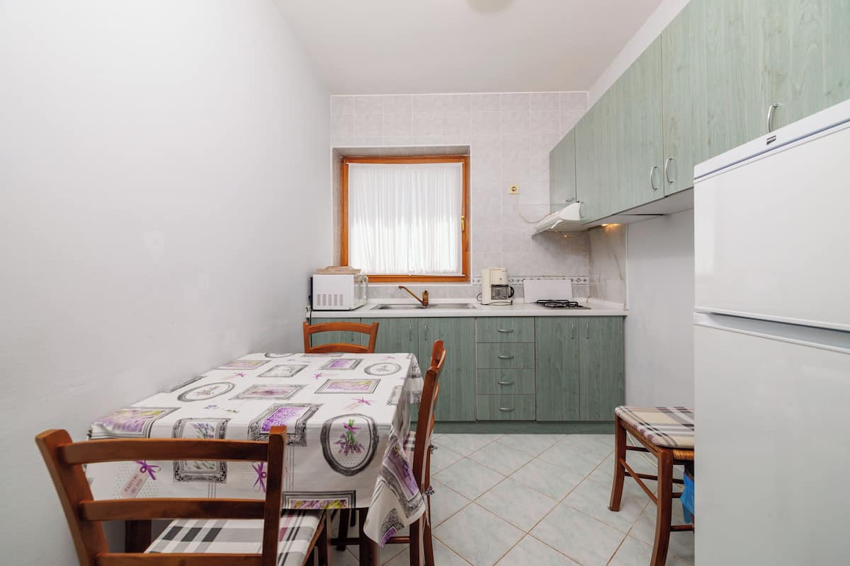 A compact kitchen with a dining table, chairs, a microwave, and a refrigerator.