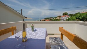 A balcony with a table set for two, a bottle of champagne, and a vase of flowers. - Apartment Marica (Lopar)