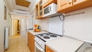 Eine Küche mit Holzausstattung, einem weißen Herd, einer Mikrowelle und einer Arbeitsplatte mit Obst und einer Kaffeemaschine.