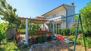 Ein Wohnhaus mit Garten, Schaukel und überdachter Terrasse.