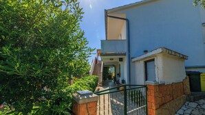 Ein Gebäude mit rustikalem Steinunterbau und weißem Obergeschoss, einer sichtbaren Tür und einem kleinen Balkon.