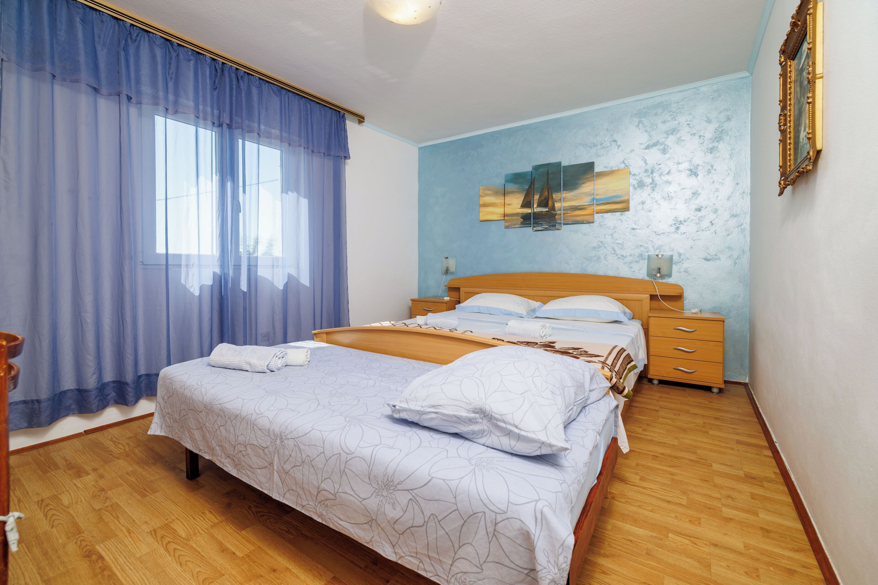 Una camera da letto con un letto di legno, un comodino, una cassettiera e un quadro appeso al muro.