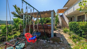 Ein Garten mit Schaukel, Holzpferd und einem Gebäude mit Treppe.