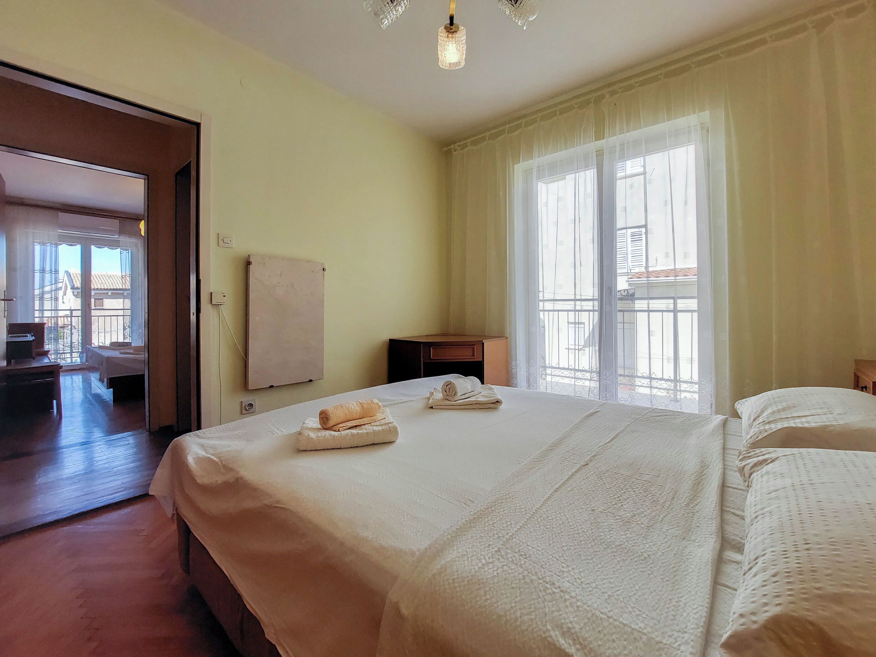 Een hotelkamer met een groot bed, een bureau en een stoel. Er is een raam met gordijnen en uitzicht op buiten.