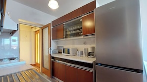 A compact kitchen with stainless steel appliances, wooden cabinets, and a built-in microwave. - Apartments Nikola (Punat)