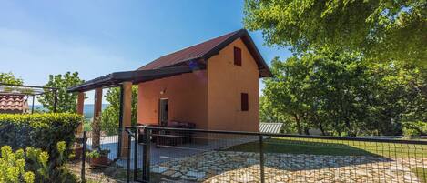 A rustic building with a sloped roof, a covered porch, and a stone-paved area.