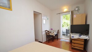 Une chambre à coucher comprenant un lit, une commode en bois, un téléviseur et un coin repas avec une table et des chaises.
