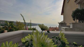 A balcony with a view of the sea and distant hills.