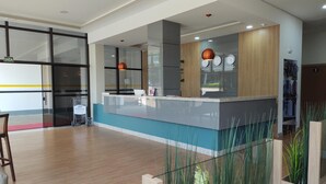 A modern hotel lobby with a reception desk, a glass partition, and a wooden floor. - Hotel Maestro Express (Francisco Beltrao)