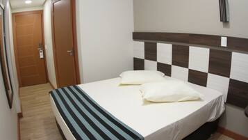 Una habitación de hotel con una cama, un cabecero a cuadros y una colcha a rayas.