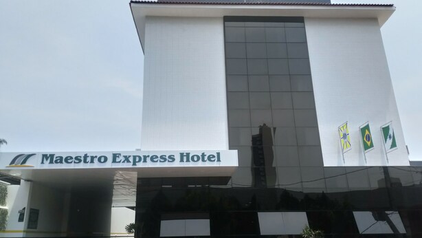 The exterior of the Maestro Express Hotel with a modern design, featuring a prominent entrance and three flags. - Hotel Maestro Express (Francisco Beltrao)