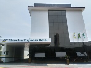 The exterior of the Maestro Express Hotel with a modern design, featuring a prominent entrance and three flags. - Hotel Maestro Express (Francisco Beltrao)