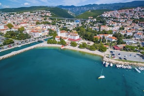 An aerial view of a coastal town with a marina, buildings, and a bridge in the background.