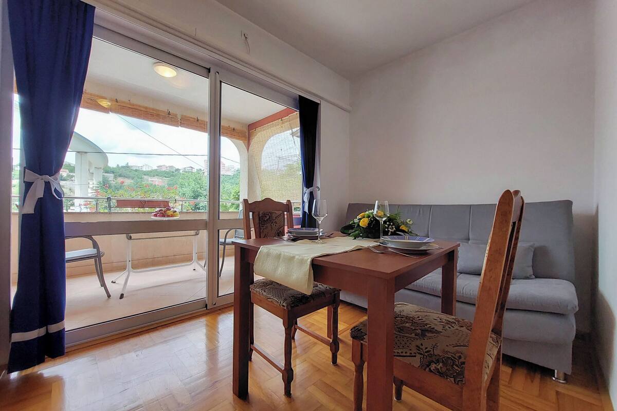 A dining area with a wooden table, chairs, and a grey sofa.