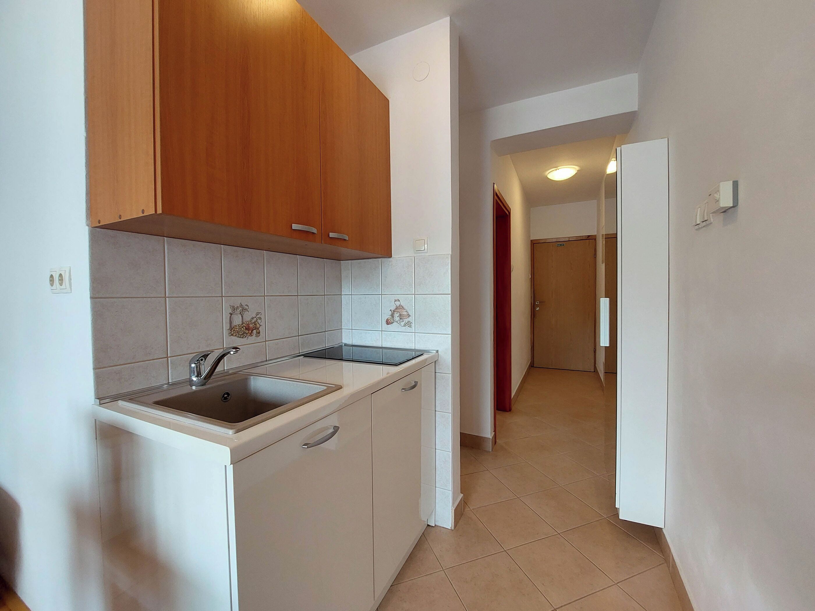 A kitchen with white cabinets, a stainless steel sink, and a tiled backsplash.