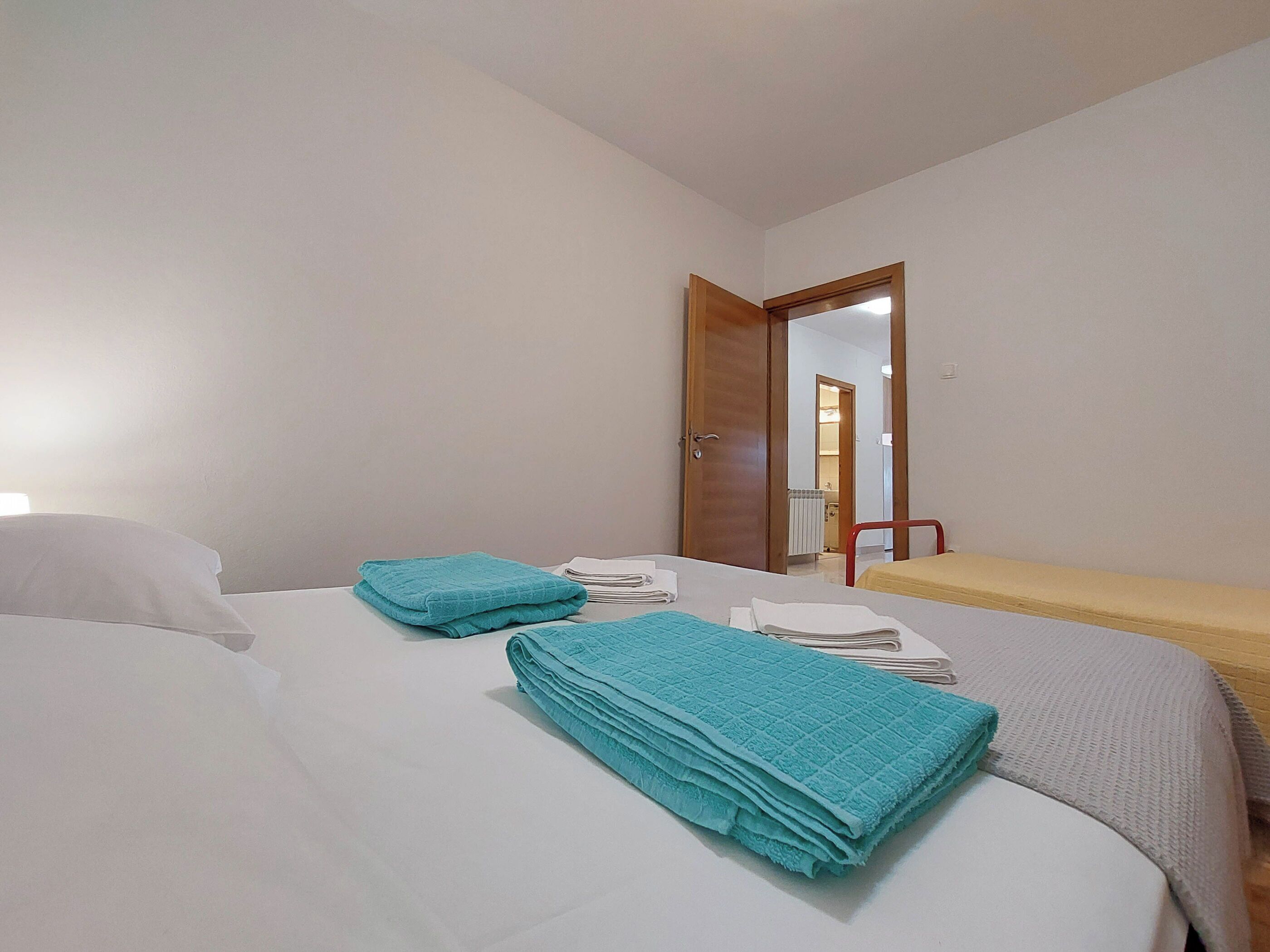 Ein Hotelzimmer mit einem Bett, einem kleinen Tisch und einer Tür zu einem weiteren Raum.