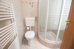 A bathroom with a toilet, a shower enclosure, and a towel rack.