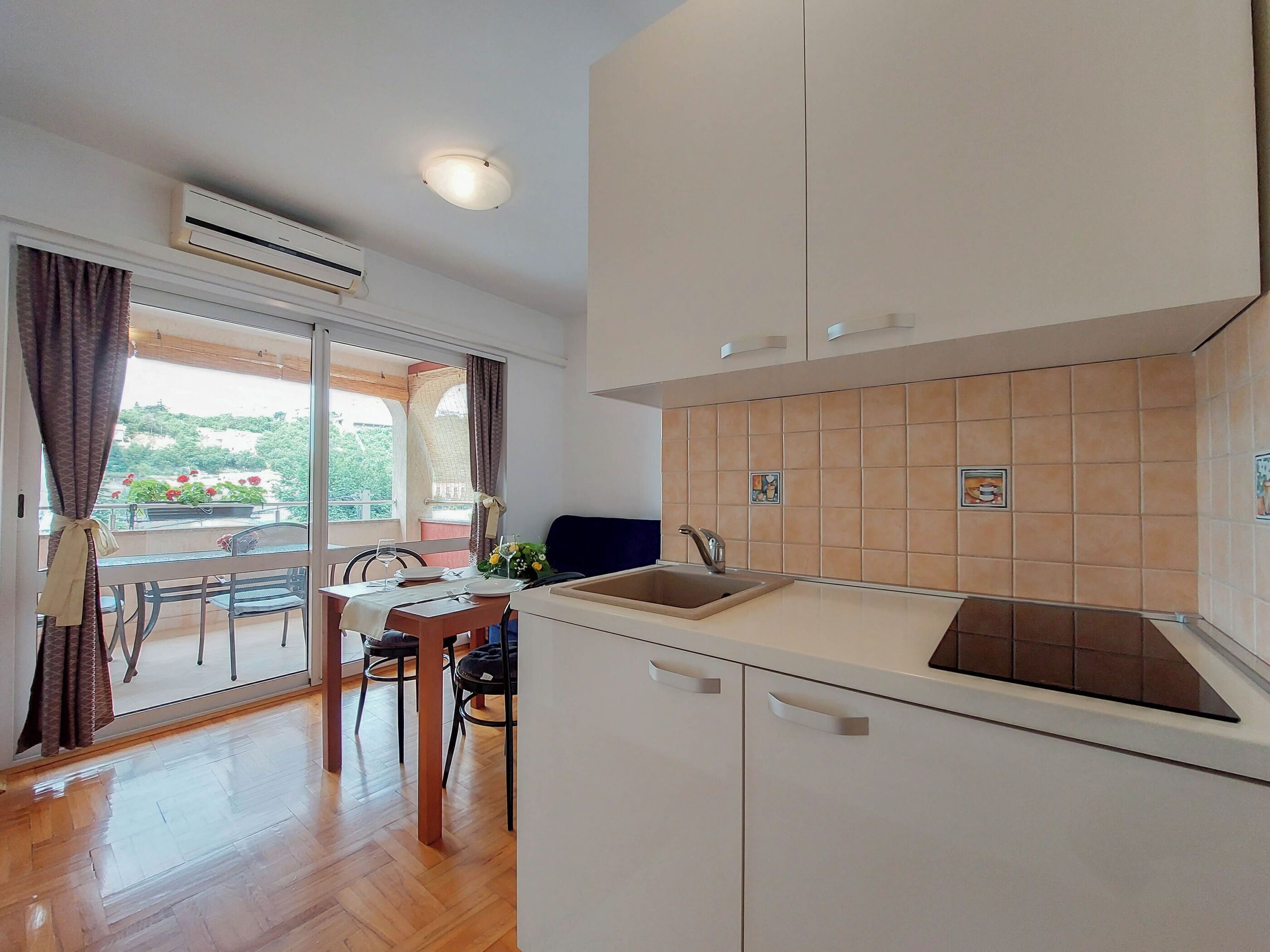 Una cocina moderna con armarios blancos, un lavamanos y una zona de comedor con una mesa y sillas.