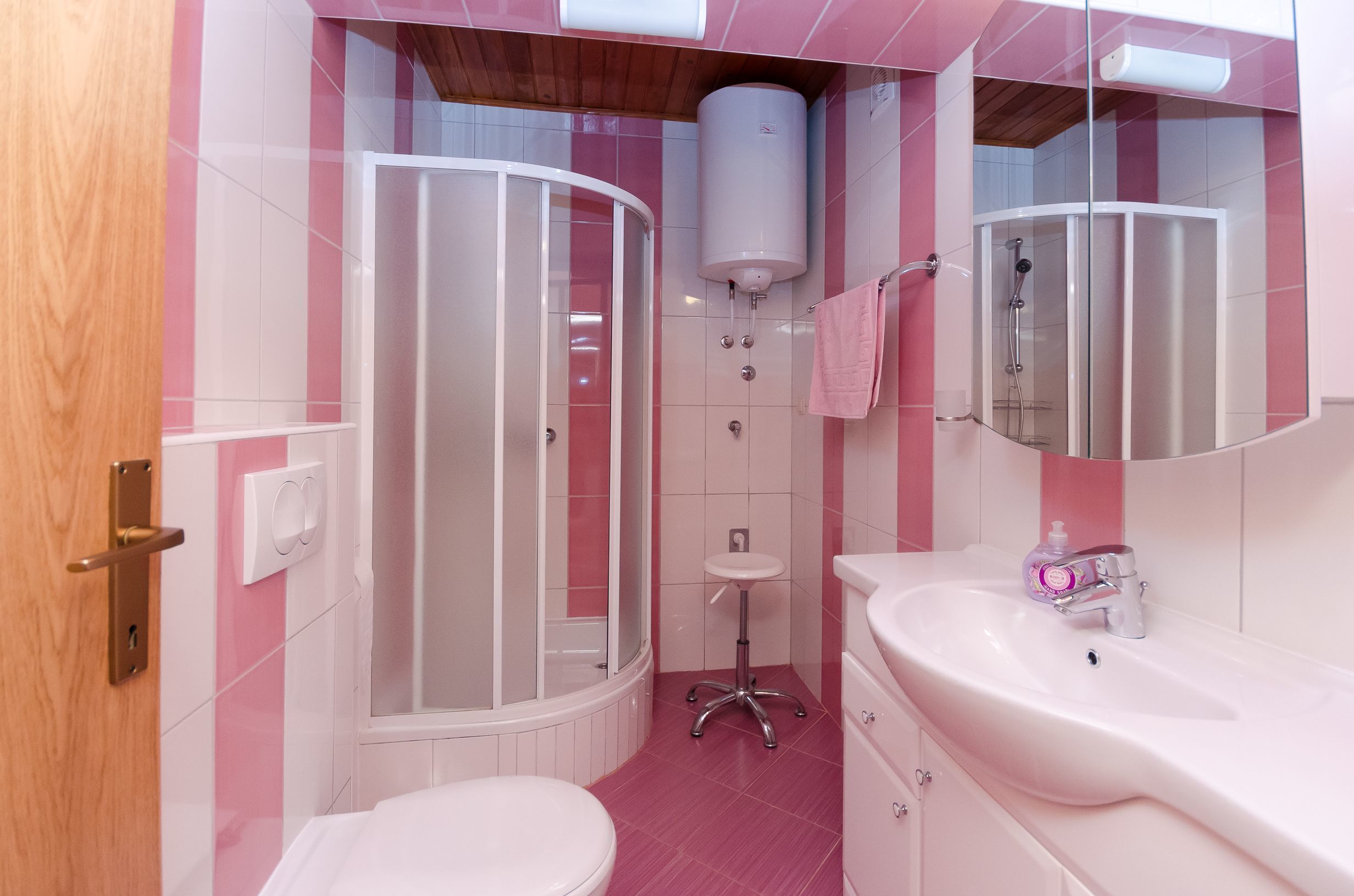 A bathroom with a shower, toilet, sink, and a mirror.