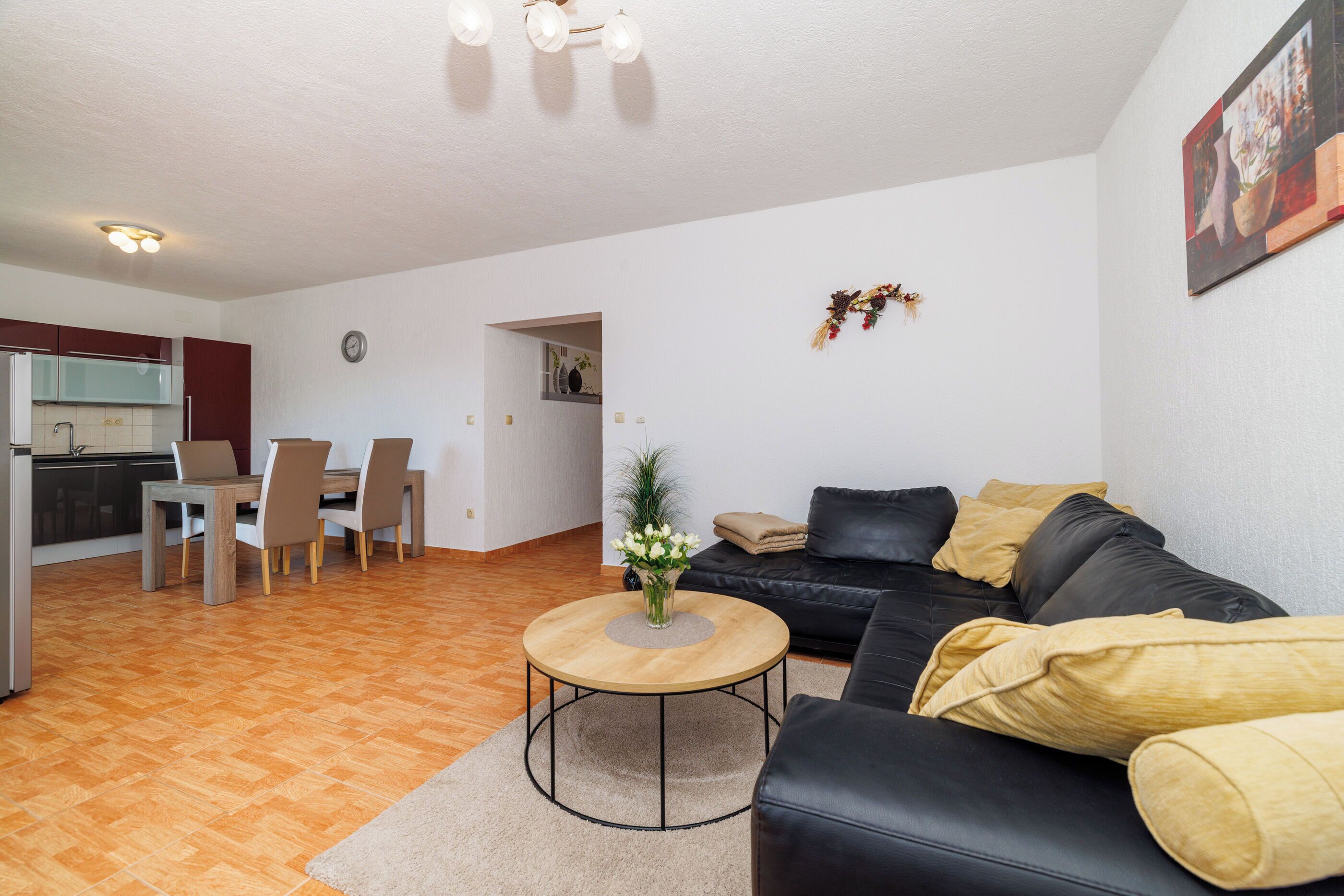 Una sala de estar moderna con un sofá negro, una mesa de centro de madera y un comedor con una mesa y sillas.