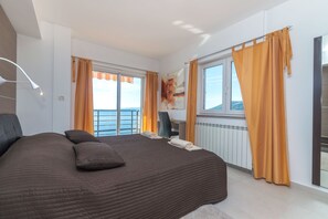 Een slaapkamer met een groot bed, een bureau en uitzicht op zee.