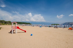 A beach with a lifeguard tower, beach umbrellas, and a tent. - Apartments Ivan (Lopar)